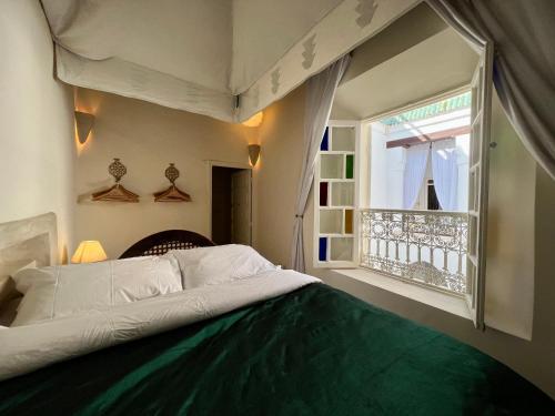 a bedroom with a bed and a window at Riad Tizwa Marrakech in Marrakech