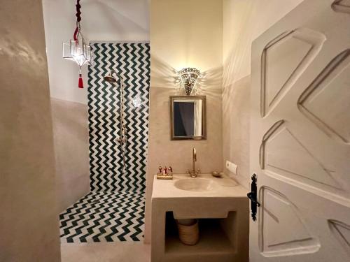 a bathroom with a sink and a black and white patterned wall at Riad Tizwa Marrakech in Marrakesh