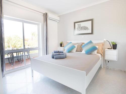 a white bedroom with a large bed and a balcony at Amigos para Sempre - Casa de Hóspedes in Ferragudo