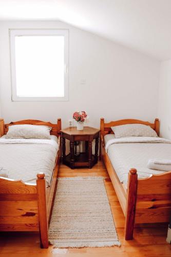 two beds in a room with a table and a window at Weekend Joy Home Visoko in Visoko