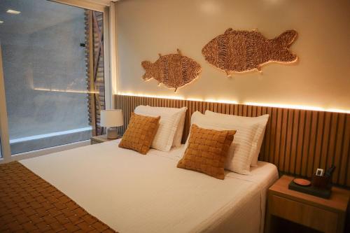 1 dormitorio con 1 cama con 2 peces en la pared en APARTAMENTO 05 - PÉ NA AREIA - BARRA BALI - AL, en Barra de São Miguel