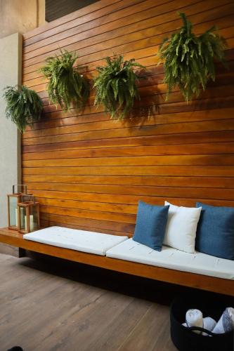 a couch against a wooden wall with potted plants at APARTAMENTO 05 - PÉ NA AREIA - BARRA BALI - AL in Barra de São Miguel