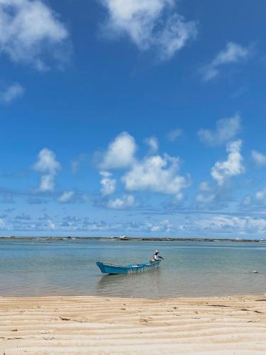 a person in a blue boat on a beach at APARTAMENTO 05 - PÉ NA AREIA - BARRA BALI - AL in Barra de São Miguel