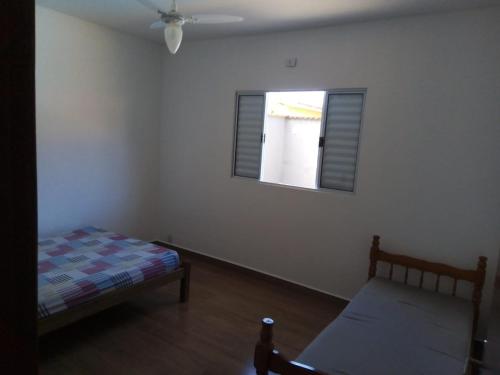 a bedroom with a bed and a window at Casa com piscina em condomínio fechado in Peruíbe