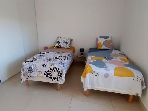 deux lits jumeaux dans une chambre aux murs blancs dans l'établissement Bel appartement Corse côte Est, à Morta