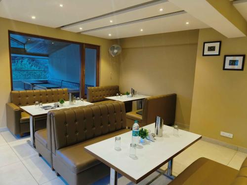a dining room with tables and chairs and a window at Sa-Ba Manali Inn, Mall Road in Manāli