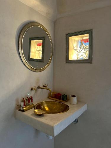a bathroom with a gold sink and a mirror at Riad Tizwa Marrakech in Marrakech