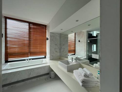 a bathroom with a tub and a sink and a mirror at La Mer Luxury Private Pool Villa in Pantai Cenang