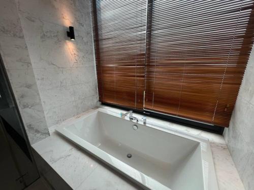 a white bath tub in a bathroom with a window at La Mer Luxury Villa - Private Pool Langkawi in Pantai Cenang