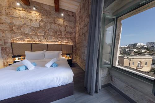 a bedroom with a bed and a large window at DOMS Boutique Living in Mellieħa