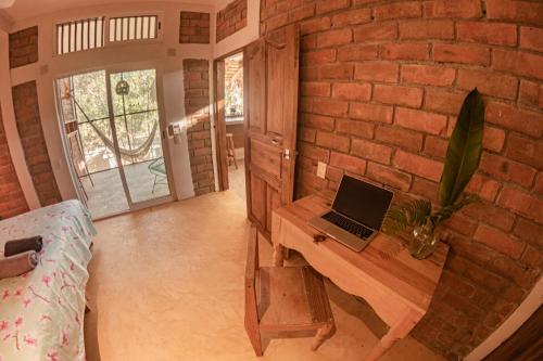 a room with a desk with a laptop on a brick wall at Casa Aquila Mazunte in Mazunte