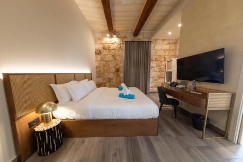 1 dormitorio con cama, escritorio y ordenador en DOMS Boutique Living en Mellieħa