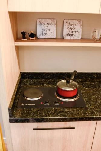 a stove top with a pot on it in a kitchen at Loft aconchegante no Parque Una in Pelotas