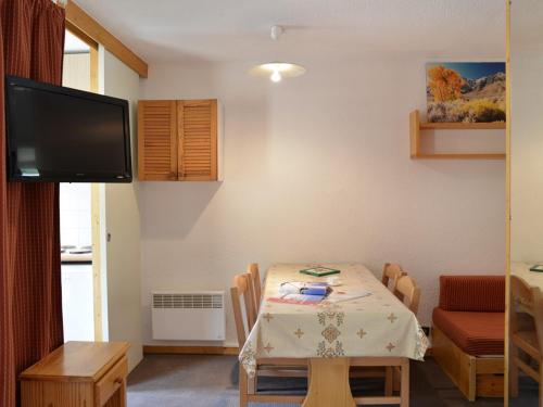 d'une salle à manger avec une table et une télévision à écran plat. dans l'établissement Studio lumineux au pied des pistes avec balcon, parking et animaux admis - FR-1-181-2224, à La Plagne Tarentaise