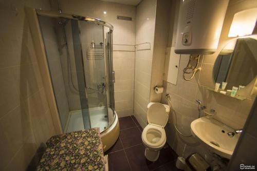 uma casa de banho com um chuveiro, um WC e um lavatório. em Orbi Royal Apartments em Batumi