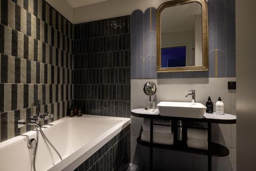 a bathroom with a tub and a sink and a mirror at Hotel L de Lutece - Notre-Dame in Paris