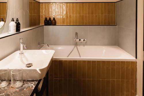 La salle de bains est pourvue d'une baignoire et d'un lavabo. dans l'établissement Hôtel L de Lutèce, à Paris