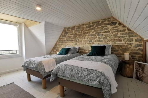 - 2 lits dans une chambre avec un mur en pierre dans l'établissement La Villa d'Anna, une décoration très tendance !, à Primelin