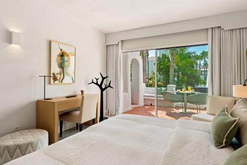 a bedroom with a bed and a desk and a table at 2-Bedroom Apartment in Puente Romano, Marbella in Marbella