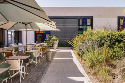 a patio with tables and chairs and an umbrella at Holiday Inn - Marseille Airport by IHG in Vitrolles