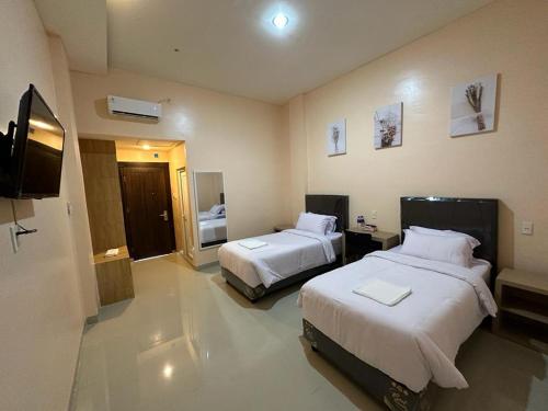 GRAND PANDAN HOTEL في Halangan: غرفه فندقيه سريرين وتلفزيون