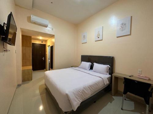 GRAND PANDAN HOTEL في Halangan: غرفة نوم بسرير ومكتب وتلفزيون