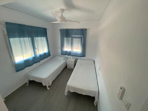 een witte kamer met een bed en 2 ramen bij Apartamento vacacional en Denia in Denia