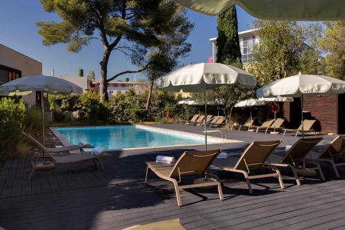a swimming pool with lounge chairs and umbrellas next to a pool at Holiday Inn - Marseille Airport, an IHG Hotel in Vitrolles