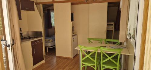 een kleine keuken met een tafel en groene krukken bij Camping Le Bourdieu in Durfort