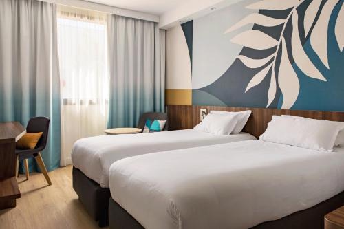 a hotel room with two beds and a desk at Holiday Inn - Marseille Airport by IHG in Vitrolles