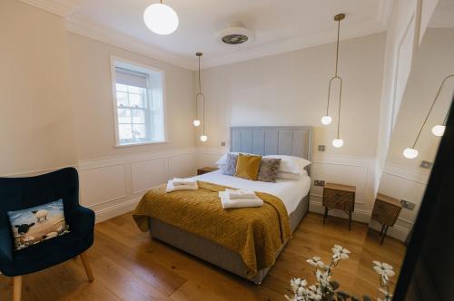 里士滿的住宿－WENSLEYDALE, OLD SCHOOL ROOMS - Ground Floor Luxury Apartment in Richmond, North Yorkshire，一间卧室配有一张床和一把椅子