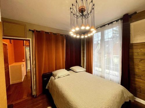 een slaapkamer met een bed en een kroonluchter bij Appartement chalet n°5 in Noisy-le-Sec