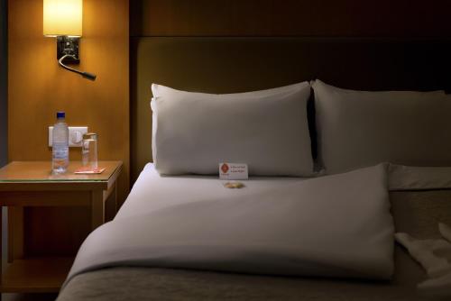 a bed with two pillows and a bottle of water on a table at Azalaï Hôtel Cotonou in Cotonou