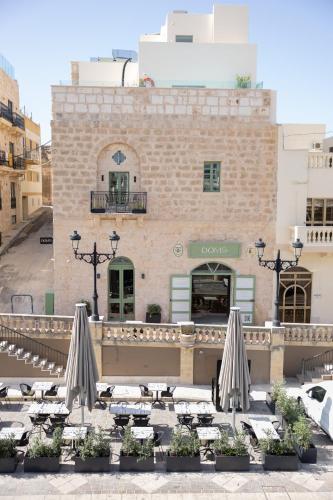 a group of tables with umbrellas in front of a building at DOMS Boutique Living in Mellieħa