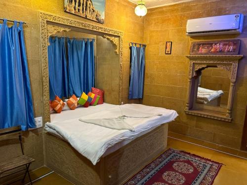 a bed in a room with a mirror and blue curtains at Hotel Pol Haveli Jaisalmer in Jaisalmer