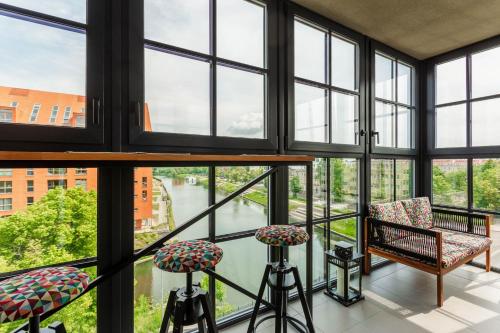 a room with large windows with chairs and a table at Rent like home - Dwie Motławy III z parkingiem in Gdańsk