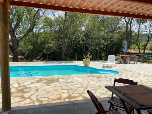 einen Pool mit einer Terrasse, einem Tisch und Stühlen in der Unterkunft Pousada Casa Ferreira in Pirenópolis
