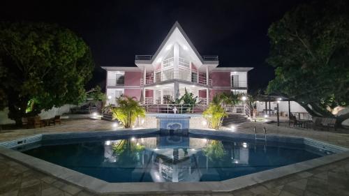 a large pink house with a swimming pool at night at Casa da Barbie na praia de Carapibus PB in Conde
