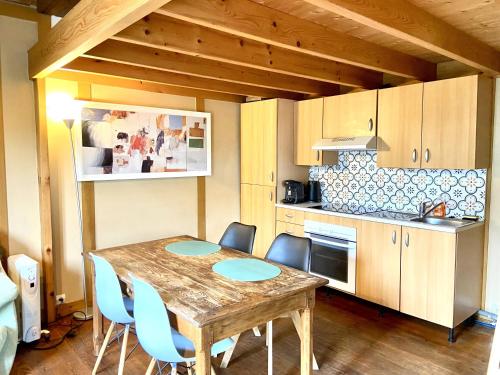 cocina con mesa de madera y sillas azules en Le chalet bucolique au bord de l'eau, en Olivet