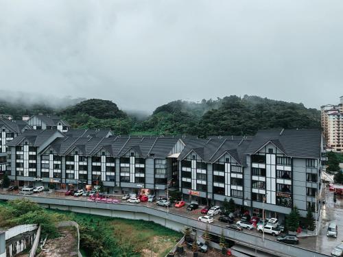 a row of apartment buildings with cars parked on a street at D'Elegant Suite - Emerald Avenue in Cameron Highlands