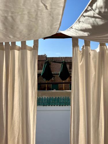 a window with white curtains in a room at Riad Tizwa Marrakech in Marrakech