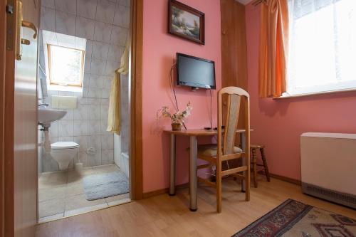 La salle de bains est pourvue d'une table, de toilettes et d'une télévision. dans l'établissement Happy Bison - A 5 Bedroom House With A Garden, à Białowieża