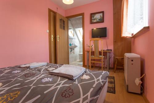 - une chambre aux murs roses avec un lit et une télévision dans l'établissement Happy Bison - A 5 Bedroom House With A Garden, à Białowieża