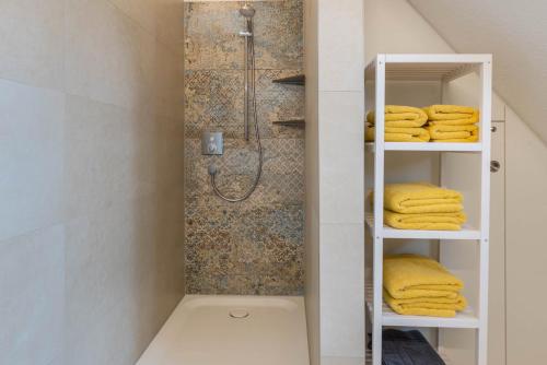 a bathroom with a shower and yellow towels on shelves at Landluft Ferien - Wohnung Abendrot in Heiligenberg