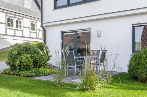 un patio con sillas y plantas frente a una casa en Ferienwohnung Grübel en Kirchhundem