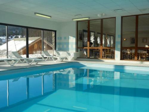 a swimming pool with chairs and a building at Chalet de 3 chambres a Le Devoluy a 200 m des pistes avec piscine partagee sauna et terrasse in Le Dévoluy