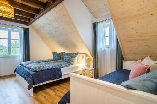 two beds in a room with wooden ceilings and windows at Landluft Ferien - Wohnung Abendrot in Heiligenberg