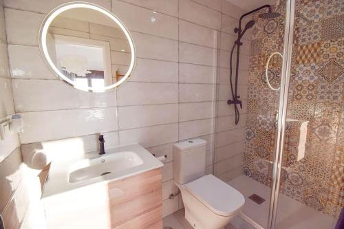 a bathroom with a toilet and a sink and a mirror at Casita Frigiliana - stunning new apartment with views with private parking space in Frigiliana
