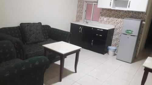 uma cozinha com um sofá, uma mesa e um frigorífico em كوتاج المفروشة em Al Khobar