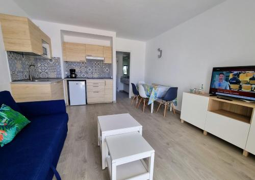 een woonkamer met een blauwe bank en een keuken bij Sands Beach - Hoy Hotels in Costa Teguise